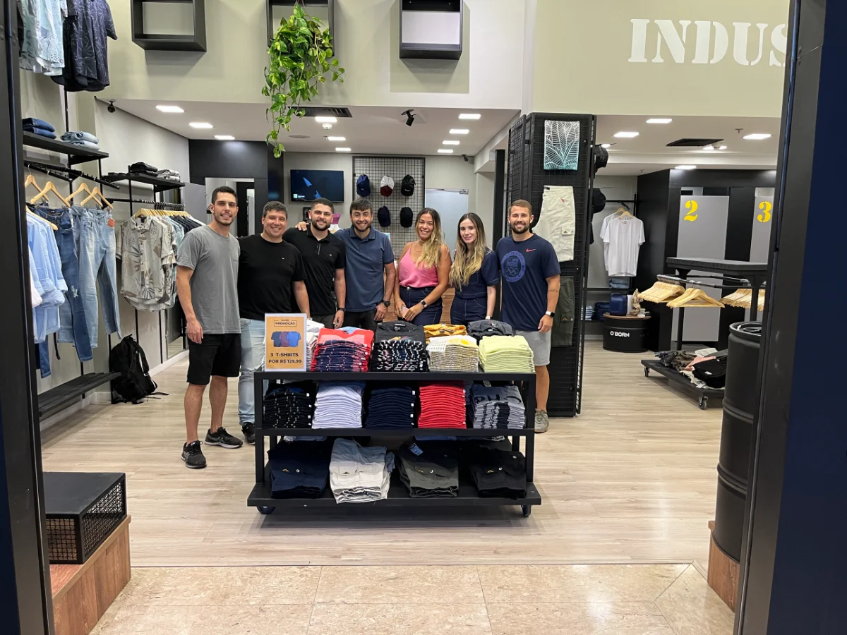 Dentro da loja de roupas que eu tocava: araras de camisas e jeans e uma mesa de camisetas dobradas